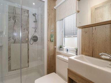 A bathroom with a shower enclosure toilet sink and a window with blinds at Pine Lake View Coniston View 3 Carnforth