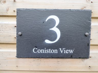 A black rectangular sign with the number 3 and the text Coniston View on a wooden wall at Pine Lake View Coniston View 3 Carnforth