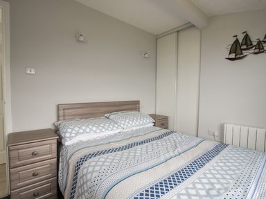 A bedroom with a double bed with patterned bedspread and two bedside tables at Sealark in Eype