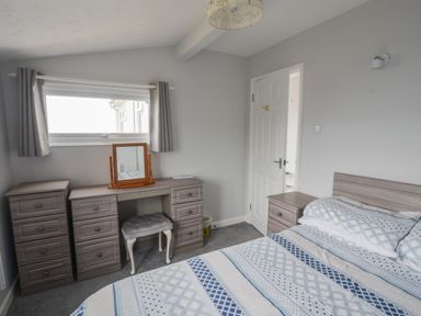 A bedroom with a bed and a dressing table with drawers and a mirror at Sealark in Eype