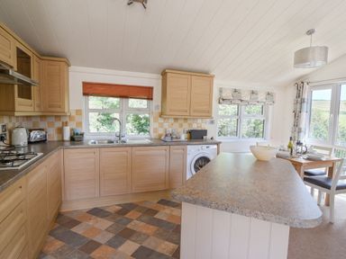 A kitchen with wooden cabinets an island and a dining table with chairs at The Hideaway in Eype