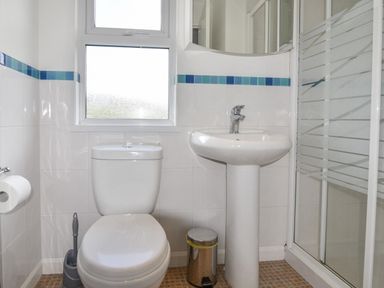 A bathroom with a toilet a sink a window and a shower at The Hideaway in Eype