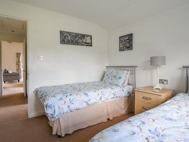 A bedroom with two single beds a wooden nightstand and a lamp at The Hideaway in Eype