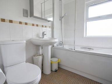 A bathroom with a toilet sink bathtub shower and window at The Hideaway in Eype