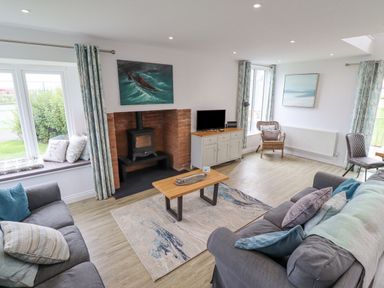 A living room with two sofas a coffee table and a wood stove at Turning Tide in Beadnell