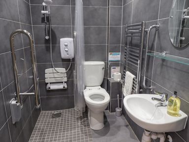 A bathroom with a toilet shower with a foldable seat sink and towel rail at Turning Tide in Beadnell