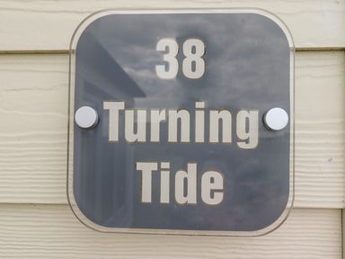 A house number sign 38 Turning Tide on a light colored exterior wall at Turning Tide in Beadnell