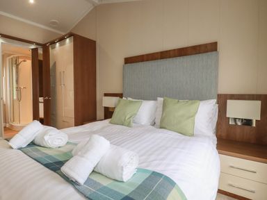 A bedroom with a double bed towels on the bed and an en suite bathroom at Haven Lodge Bossiney Bay near Tintagel