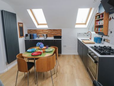 A kitchen with dining table set for four under skylight windows at The Loft @ Wisteria Cottage in Saundersfoot