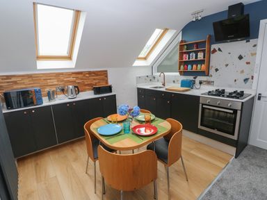 A kitchen with black cabinets wooden dining table with colorful plates and glasses and skylights at The Loft @ Wisteria Cottage in Saundersfoot