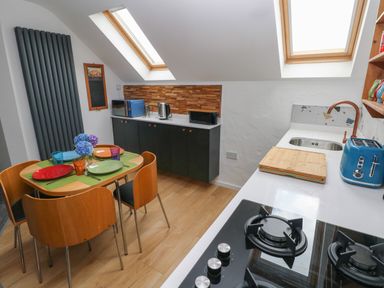 A kitchen with a dining table set for four under skylights at The Loft @ Wisteria Cottage in Saundersfoot