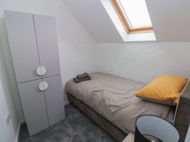 A small bedroom with a single bed a gray wardrobe a skylight window and a lamp at The Loft @ Wisteria Cottage in Saundersfoot