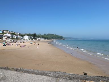 A sandy beach with people near the water and houses along the shore at The Loft @ Wisteria Cottage in Saundersfoot
