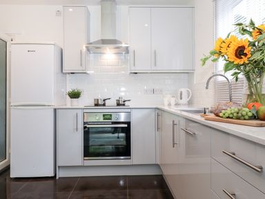 A kitchen with white cabinets a refrigerator stove oven sink and a vase of sunflowers at Watersong in Coniston