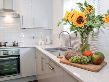 A kitchen countertop with sunflowers in a vase bread fruit and grapes on a cutting board at Watersong in Coniston