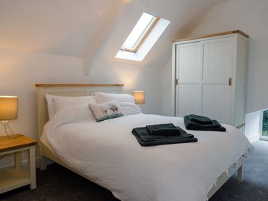 A bedroom with a bed two bedside tables lamps a wardrobe and a skylight window at School Lodge in Llandeilo