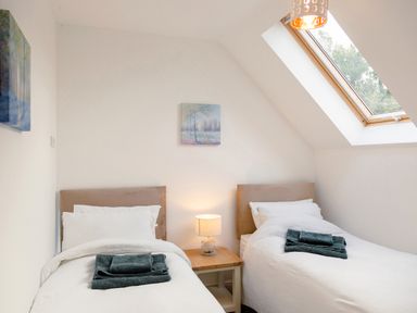 A bedroom with two single beds a wooden bedside table and a skylight window at School Lodge in Llandeilo