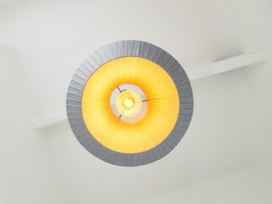 A ceiling light fixture with a lit bulb and a circular lampshade at School Lodge in Llandeilo