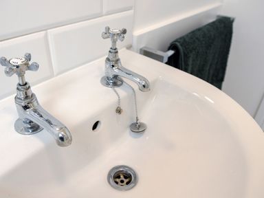 A bathroom sink with separate hot and cold taps and a towel hanging on a rack at School Lodge in Llandeilo