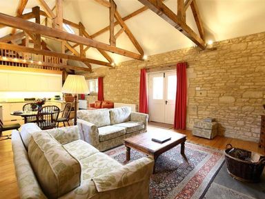 A living room with two sofas a wooden coffee table wooden beams and stone walls at The Granary in Bourton-On-The-Water