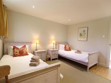 A bedroom with two single beds with bedside tables and lamps at The Granary in Bourton-On-The-Water