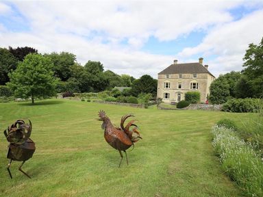 A large lawn with metal bird sculptures and a house in the background at The Granary in Bourton-On-The-Water