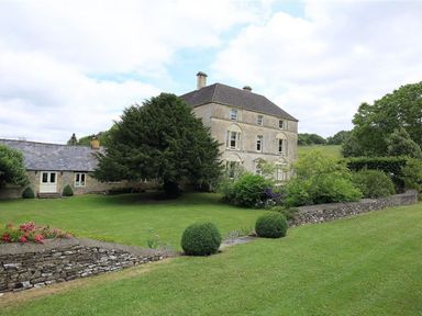 A stone house with a lawn garden and trees at The Granary in Bourton-On-The-Water