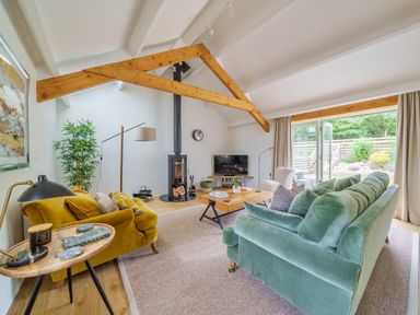 A living room with green and yellow sofas a wood stove and a wooden coffee table at The Granary in Davidstow near Camelford