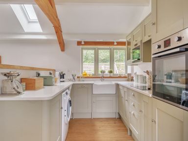A kitchen with cabinets appliances a window and wooden ceiling beams at The Granary in Davidstow near Camelford