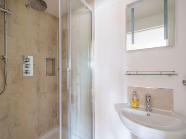 A bathroom with a glass shower enclosure and a sink with a mirror above at The Granary in Davidstow near Camelford