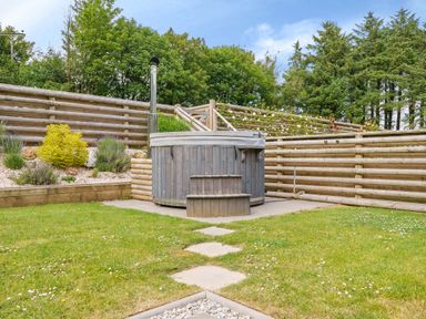 A backyard with a wooden hot tub surrounded by wooden fencing and plants at The Granary in Davidstow near Camelford