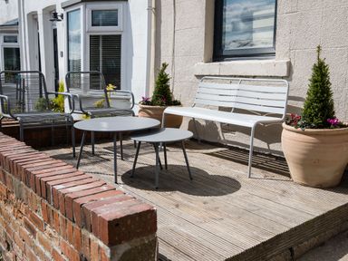 An outdoor seating area with two metal chairs two round tables a metal bench and potted plants at Casa Formentera in Scarborough