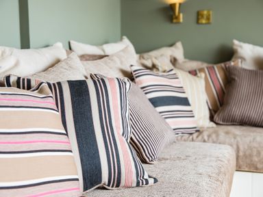 A close-up of a sofa with multiple striped and plain cushions in a room at Casa Formentera in Scarborough