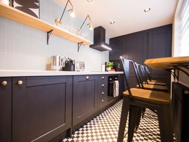 A kitchen with black cabinets a checkered floor bar stools and appliances on the counter at Casa Formentera in Scarborough