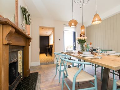 A dining room with a wooden table set for a meal blue chairs and a fireplace at Casa Formentera in Scarborough