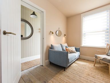 A small living room with a blue sofa a chair a mirror on the wall and a large window at Casa Formentera in Scarborough
