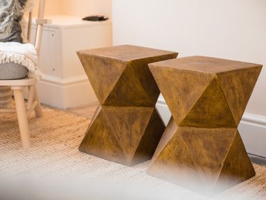Two wooden geometric stools on a rug beside a chair in a room at Casa Formentera in Scarborough