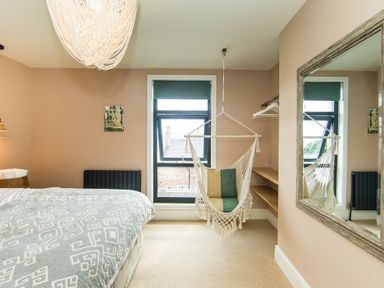 A bedroom with a bed a hanging chair a large mirror and a window at Casa Formentera in Scarborough