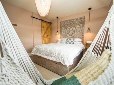 A bedroom with a bed and wall hanging viewed through a hammock at Casa Formentera in Scarborough