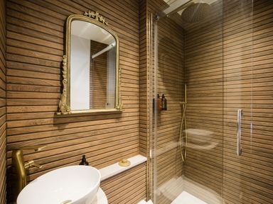 A bathroom with a round white sink golden faucet a gold framed mirror and a glass shower enclosure at Casa Formentera Scarborough