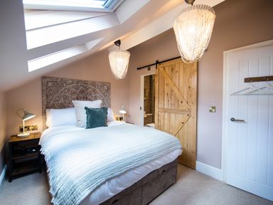 A bedroom with a double bed under skylight windows and wooden sliding door at Casa Formentera in Scarborough