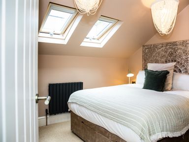 A bedroom with a bed with green and white bedding two skylight windows and a decorative headboard at Casa Formentera in Scarborough