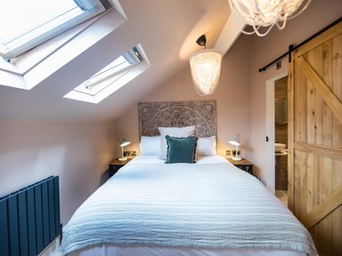 A bedroom with a bed under skylights and a wooden sliding door at Casa Formentera in Scarborough