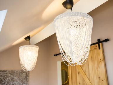 Two hanging ceiling light fixtures with white string design and a wooden sliding barn door