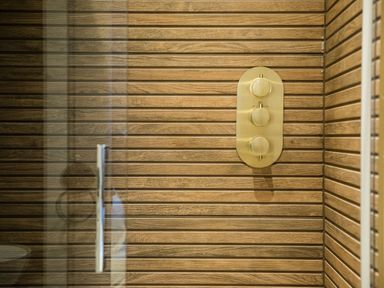 A shower area with wooden panel walls and a control panel with three knobs at Casa Formentera in Scarborough