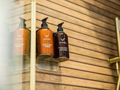 Two dispenser bottles of Odyssey shampoo and conditioner on a wall-mounted holder in a bathroom at Casa Formentera in Scarborough