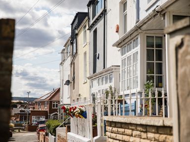 A street with terraced houses and flowerpots on a white fence at Casa Formentera in Scarborough
