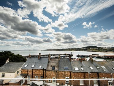 A coastal view with rooftops and a marina by the sea under a cloudy sky at Casa Formentera in Scarborough