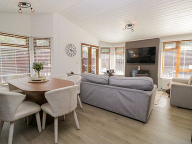A living room with a sofa and dining area at Ruskin Lodge, Langdale 16, White Cross Bay near Windermere