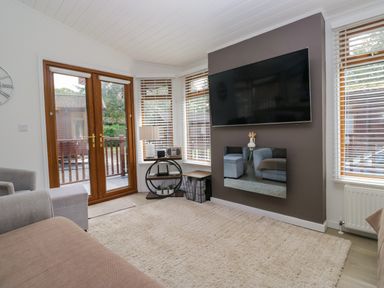 A living room with a television and sofa at Ruskin Lodge Langdale 16, White Cross Bay near Windermere